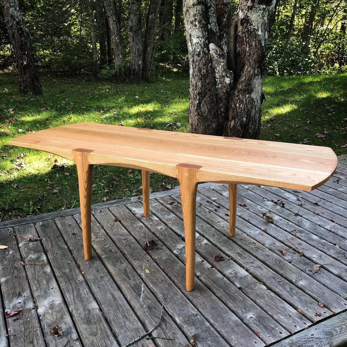 Light oak table with a natural edge on a deck