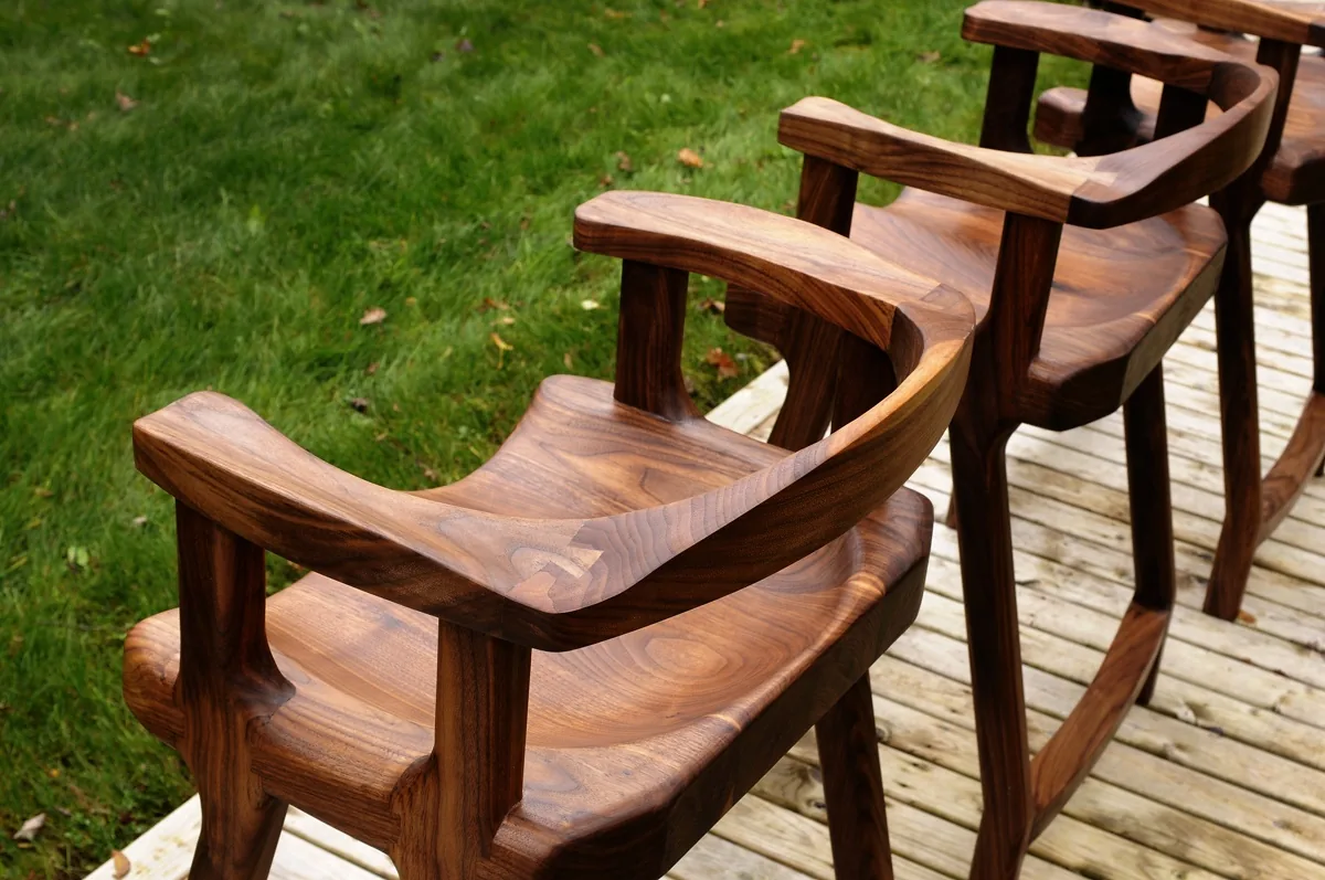 Walnut stools with curved backs on a deck